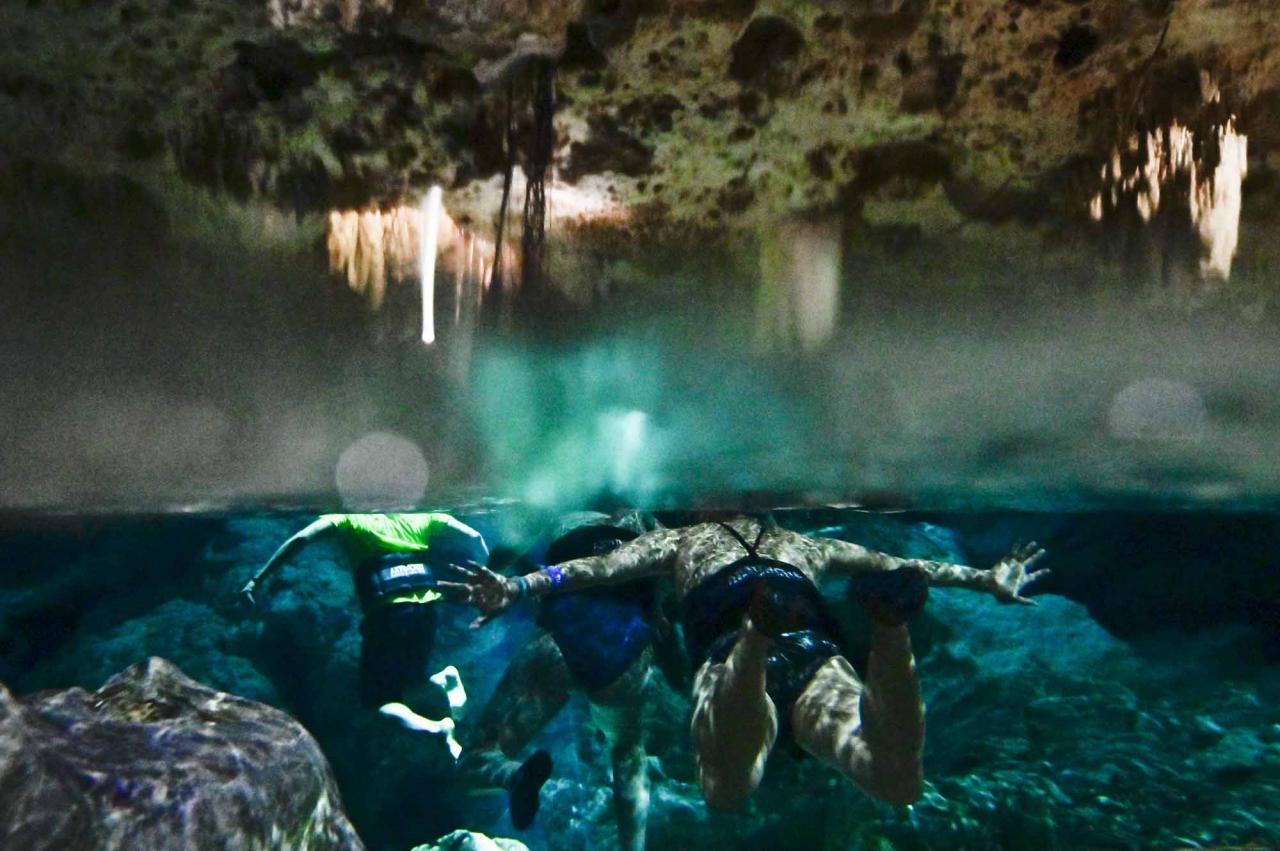Tourists swim in a water-filled sinkhole known as cenote at Aktun Chen natural park, near the construction site of Section 5 South of the Mayan Train between the resorts of Playa del Carmen and Tulum which was halted by a district judge pending resolution of an injunction sought by scuba divers and environmentalists -- in Akumal, Tulum, Quintana Roo State, Mexico, on April 27, 2022. - A Mexican judge earlier this month suspended construction of part of President Andres Manuel Lopez Obrador's flagship tourist train project in the Yucatan peninsula due to a lack of environmental impact studies. The Mayan Train, a roughly 1,500-kilometre (950 mile) rail loop linking popular Caribbean beach resorts and archeological ruins, has met with opposition from environmentalists and indigenous communities. (Photo by Pedro PARDO / AFP)