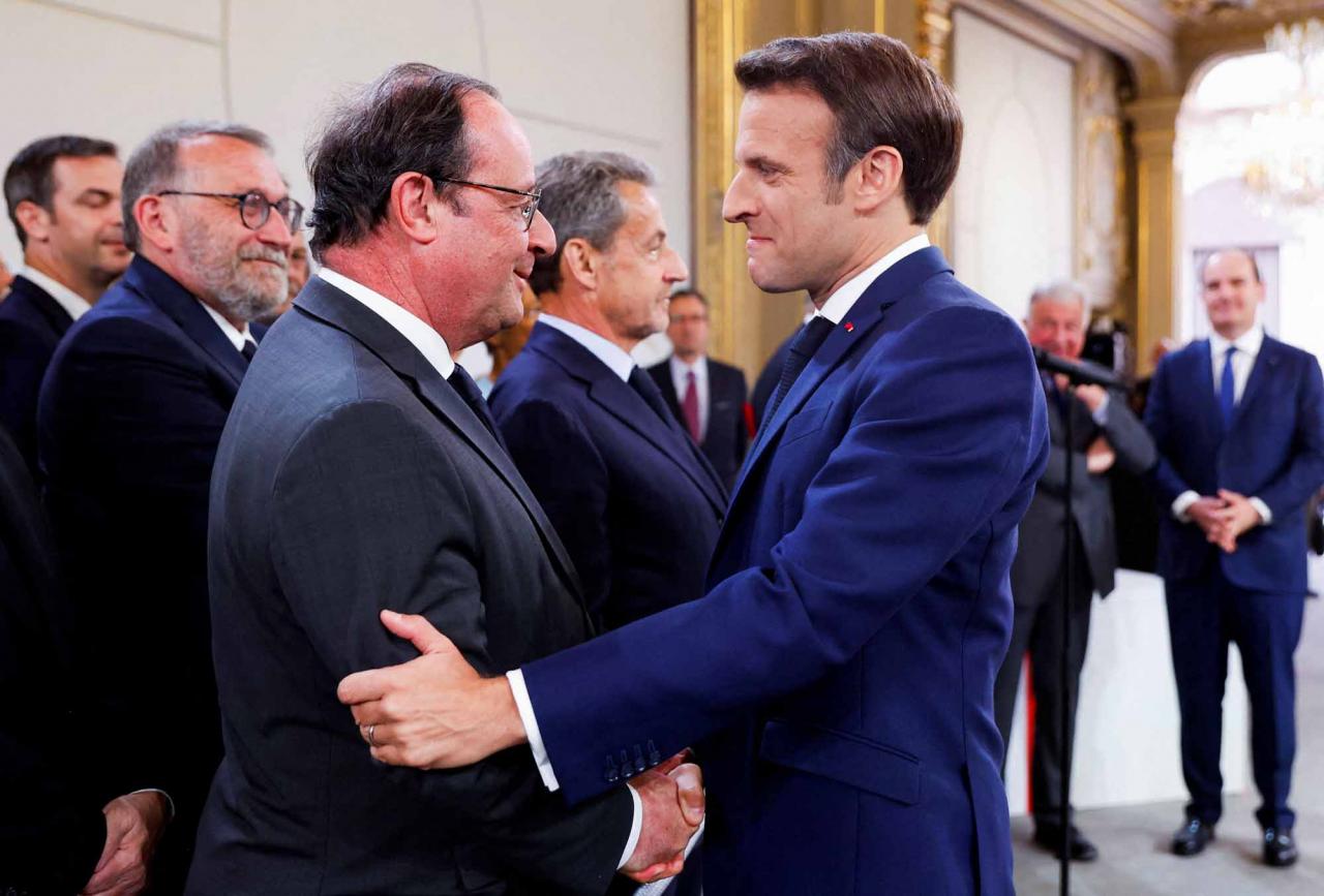 France's former President Francois Hollande (L) congratulates French President Emmanuel Macron after he is sworn-in for a second term as president following his re-election on April 14, during a ceremony at the Elysee Palace in Paris, on May 7, 2022. (Photo by GONZALO FUENTES / POOL / AFP)