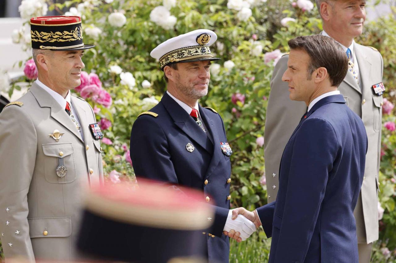 Emmanuel Macron (R) shakes hands with French Army chief of staff General Thierry Burkhard (L) and French admiral Jean-Philippe Rolland (C) chief of the particular staff of French president as he reviews troops at the Elysee presidential palace in Paris on May 7, 2022, during his investiture ceremony as French President, following his re-election last April 24. (Photo by Ludovic MARIN / AFP)