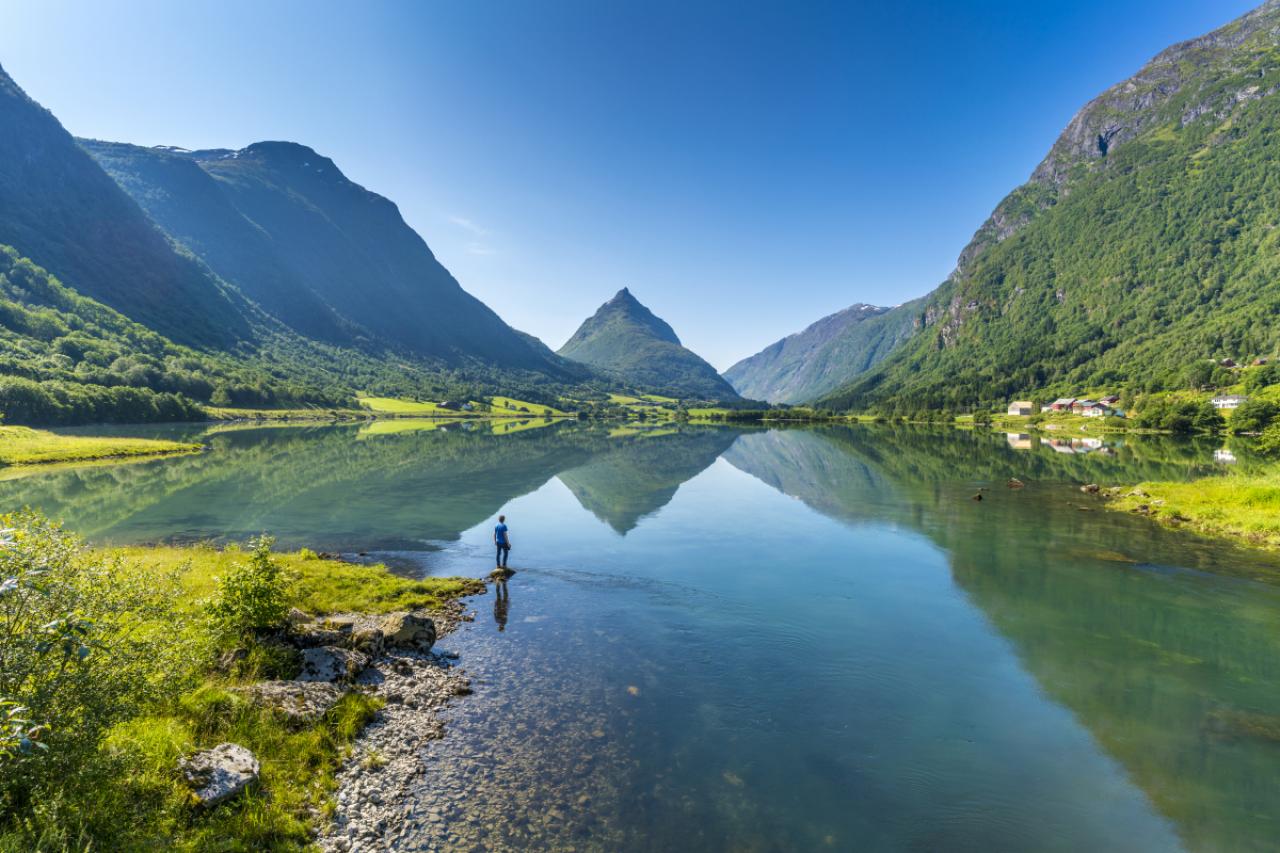 Man on banks of lake Bergheimsvatnet admiring Mount Eggenipa along the western fjords, Nordfjord, Sogn og Fjordane, Norway