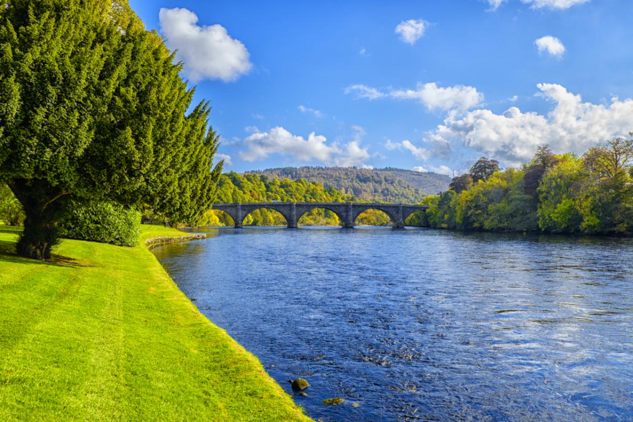 Bend in the River Tay, the longest river in Scotland at Dunkeld with Thomas Telford designed bridge. Taken in autumn on a sunny day with grass and foliage still vivid green.