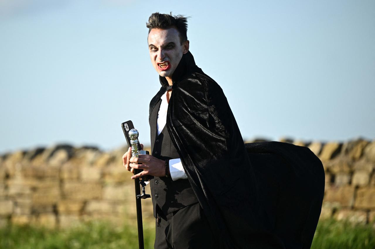 A vampire walks in the grounds of Whitby Abbey ahead of a Guinness world record attempt to gather the largest number of vampires together in one place, in Whitby, north-east England on May 26, 2022. - The world record attempt takes place on the 125th anniversary of the first publication of Bram Stoker's novel 'Dracula'. Stoker visited Whitby in 1890 and it's understood that the town and 13th century gothic ruins of the Abbey provided inspiration for Dracula. The current record saw 1039 vampires gather at Doswell in Virginia, USA in 2011. (Photo by Oli SCARFF / AFP)