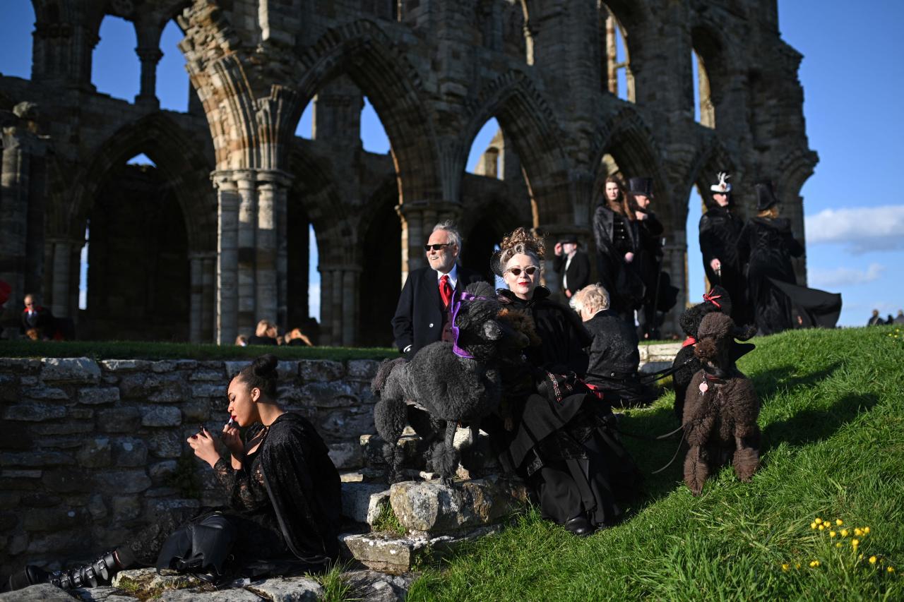 Vampires wait in the grounds of Whitby Abbey during a Guinness world record attempt to gather the largest number of vampires together in one place, in Whitby, north-east England on May 26, 2022. - The world record attempt takes place on the 125th anniversary of the first publication of Bram Stoker's novel 'Dracula'. Stoker visited Whitby in 1890 and it's understood that the town and 13th century gothic ruins of the Abbey provided inspiration for Dracula. The current record saw 1039 vampires gather at Doswell in Virginia, USA in 2011. (Photo by Oli SCARFF / AFP)