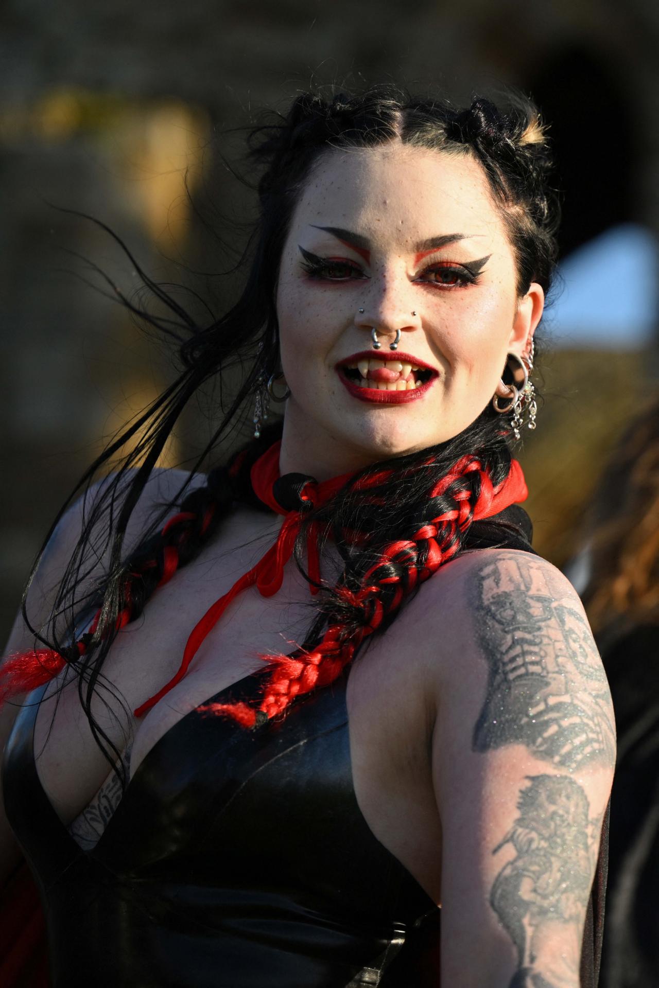 A vampire waits in the grounds of Whitby Abbey during a Guinness world record attempt to gather the largest number of vampires together in one place, in Whitby, north-east England on May 26, 2022. - The world record attempt takes place on the 125th anniversary of the first publication of Bram Stoker's novel 'Dracula'. Stoker visited Whitby in 1890 and it's understood that the town and 13th century gothic ruins of the Abbey provided inspiration for Dracula. The current record saw 1039 vampires gather at Doswell in Virginia, USA in 2011. (Photo by Oli SCARFF / AFP)