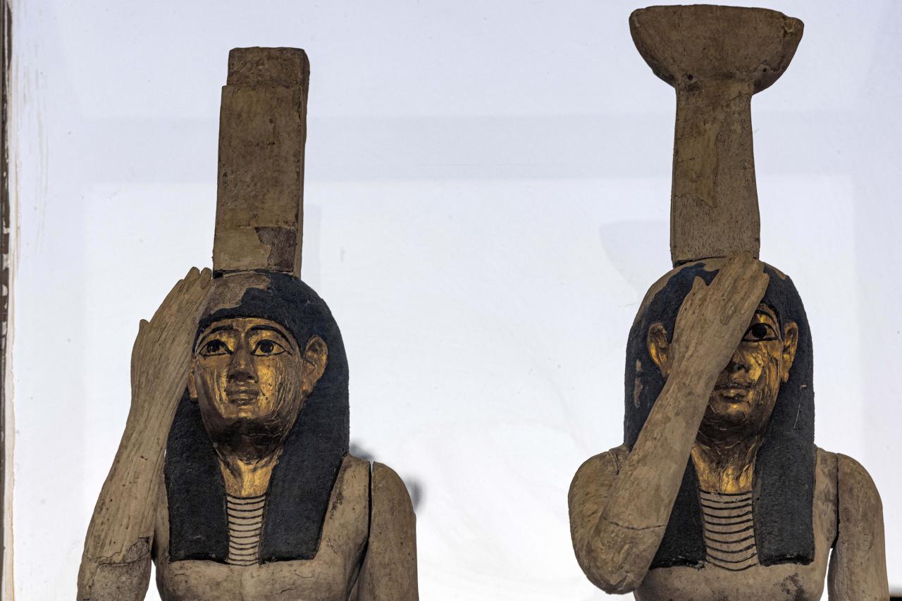 Statuettes depicting the Egyptian goddesses (L to R) Isis (Iset) and Nephthys (Nebet-Het) found in a cache dating to the Egyptian Late Period (around the fifth century BC) are displayed after their discovery by a mission headed by Egypt's Supreme Council of Antiquities, at the Bubastian cemetery at the Saqqara necropolis, southwest of Egypt's capital on May 30, 2022. - Egypt on May 30 unveiled a cache of 150 bronze statues depicting various gods and goddesses including "Bastet, Anubis, Osiris, Amunmeen, Isis, Nefertum and Hathor," along with 250 sarcophagi at the Saqqara archaeological site south of Cairo, the latest in a series of discoveries in the area. (Photo by Khaled DESOUKI / AFP)