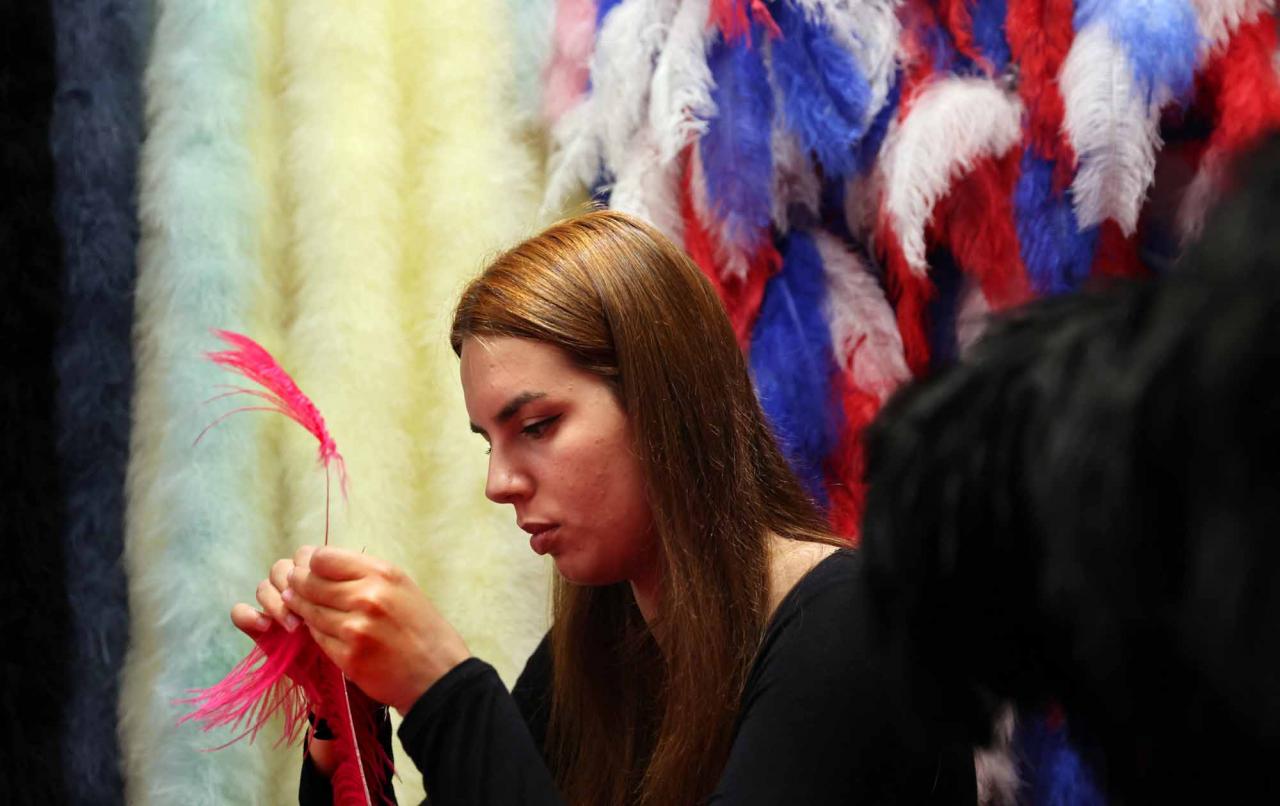 An assistant of Dominique De Roo, official feather craftsman of the Lido cabaret, works on a feather costume inside the workshop, in Paris, on June 1, 2022. - The Lido cabaret, an institution for Parisian night life since 1889, is set to lay off 157 of 184 employees, including its "Bluebell girls" troupe of dancers, announced the new owner, French hotels giant Accor. (Photo by Thomas COEX / AFP)