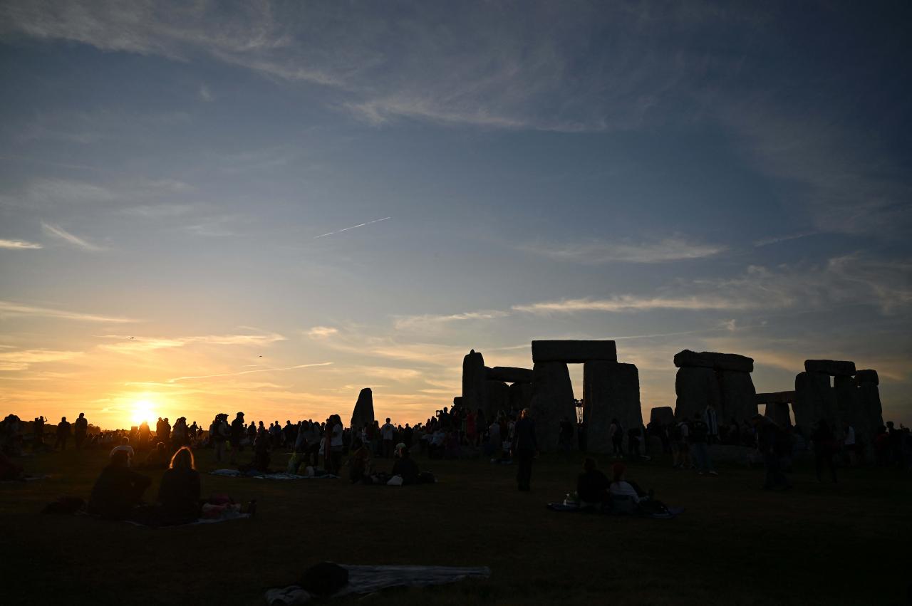 The sun sets behind the stones at Stonehenge, near Amesbury, in Wiltshire, southern England on June 20, 2022, on the eve of a festival, dating back thousands of years, that will celebrate the longest day of the year when the sun will be at its maximum elevation. - The stone monument -- carved and constructed at a time when there were no metal tools -- symbolises Britain's semi-mythical pre-historic period, and has spawned countless legends. (Photo by Justin TALLIS / AFP)