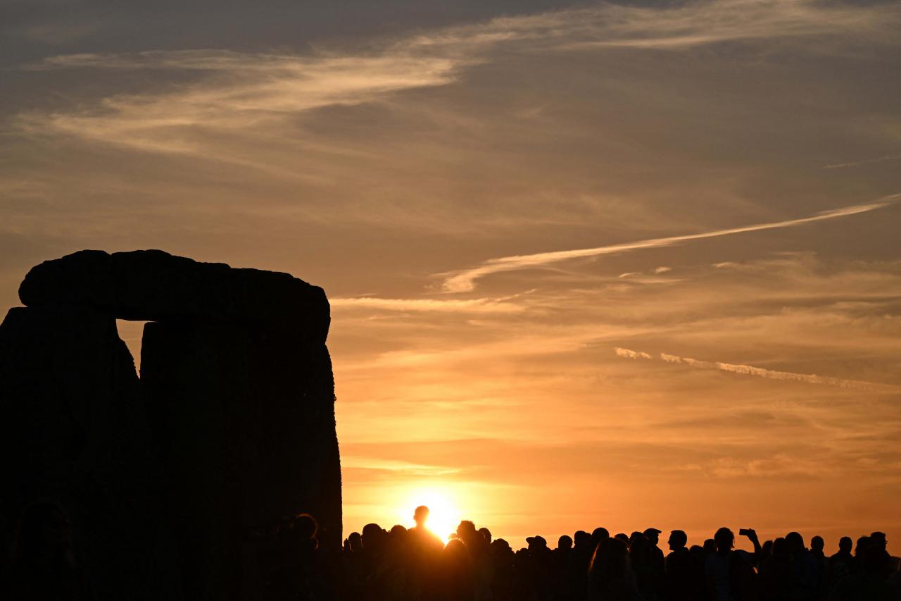 The sun sets near the stones at Stonehenge, near Amesbury, in Wiltshire, southern England on June 20, 2022, on the eve of a festival, dating back thousands of years, that will celebrate the longest day of the year when the sun will be at its maximum elevation. - The stone monument -- carved and constructed at a time when there were no metal tools -- symbolises Britain's semi-mythical pre-historic period, and has spawned countless legends. (Photo by Justin TALLIS / AFP)