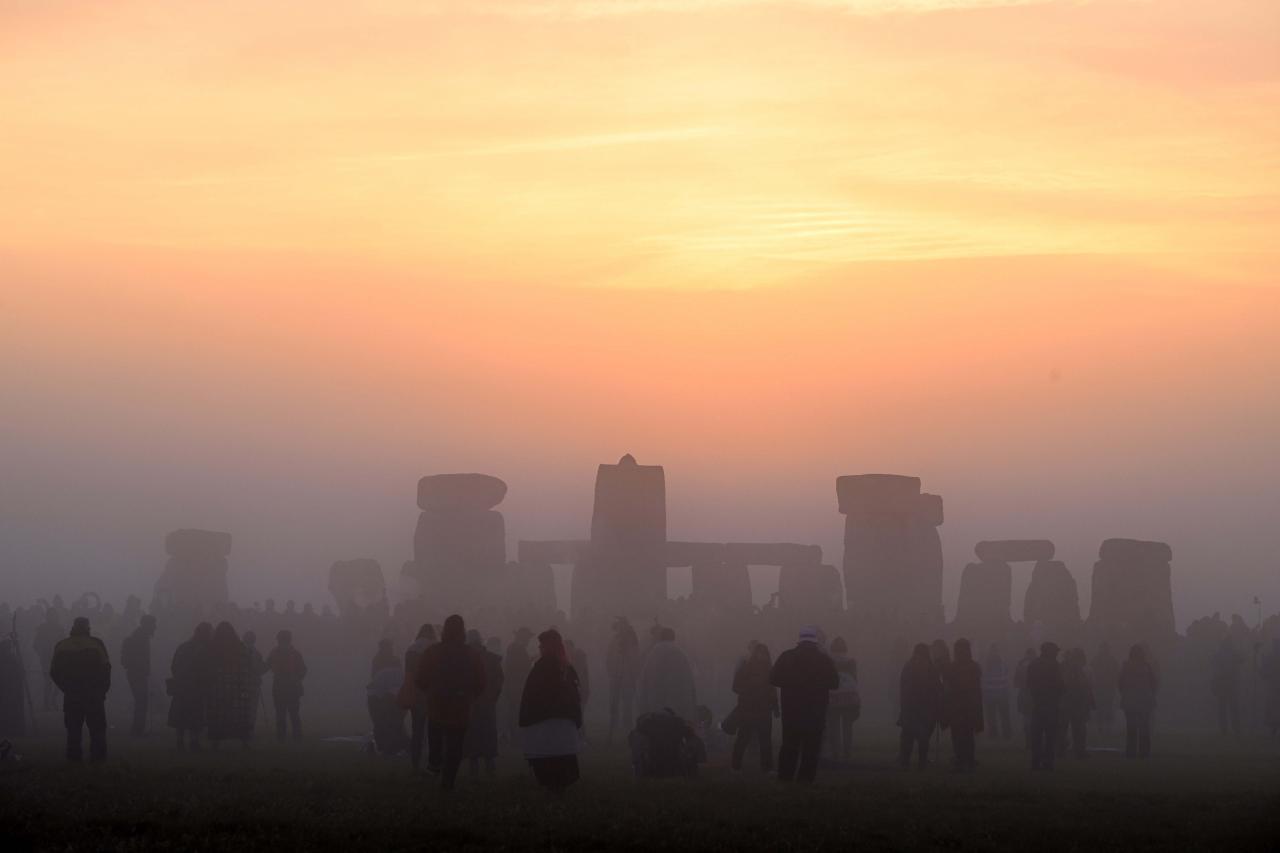Revellers celebrate the Summer Solstice as the sun rises at Stonehenge, near Amesbury, in Wiltshire, southern England on June 21, 2022, in a festival, which dates back thousands of years, celebrating the longest day of the year when the sun is at its maximum elevation. - The stone monument -- carved and constructed at a time when there were no metal tools -- symbolises Britain's semi-mythical pre-historic period, and has spawned countless legends. (Photo by Justin TALLIS / AFP)