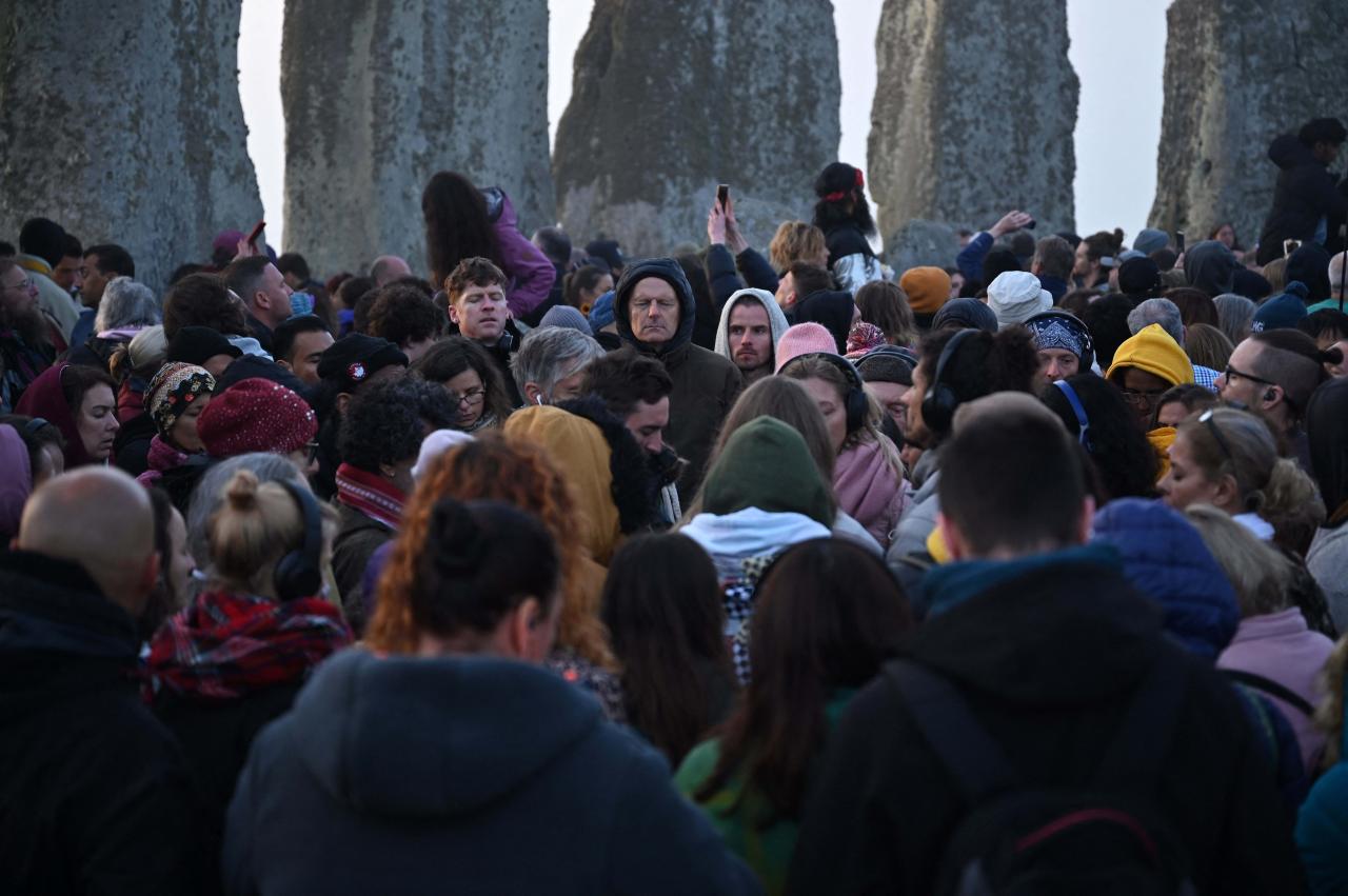 Revelers interact with the stone monument as they celebrate the Summer Solstice as the sun rises at Stonehenge, near Amesbury, in Wiltshire, southern England on June 21, 2022, in a festival, which dates back thousands of years, celebrating the longest day of the year when the sun is at its maximum elevation. - The stone monument -- carved and constructed at a time when there were no metal tools -- symbolises Britain's semi-mythical pre-historic period, and has spawned countless legends. (Photo by Justin TALLIS / AFP)