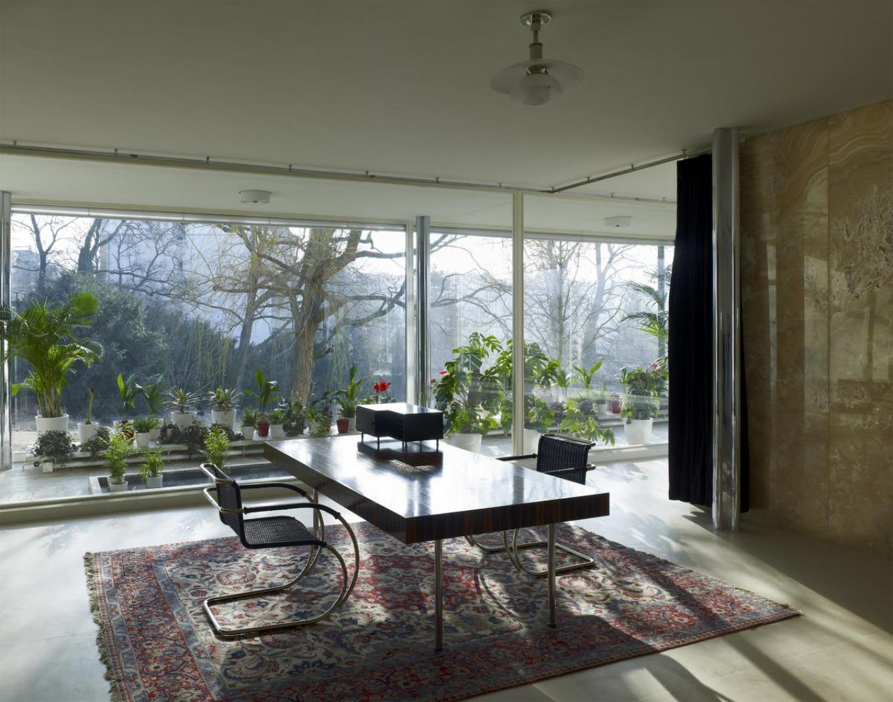 De woonkamer van Villa Tugendhat met zicht op de groene omgeving.