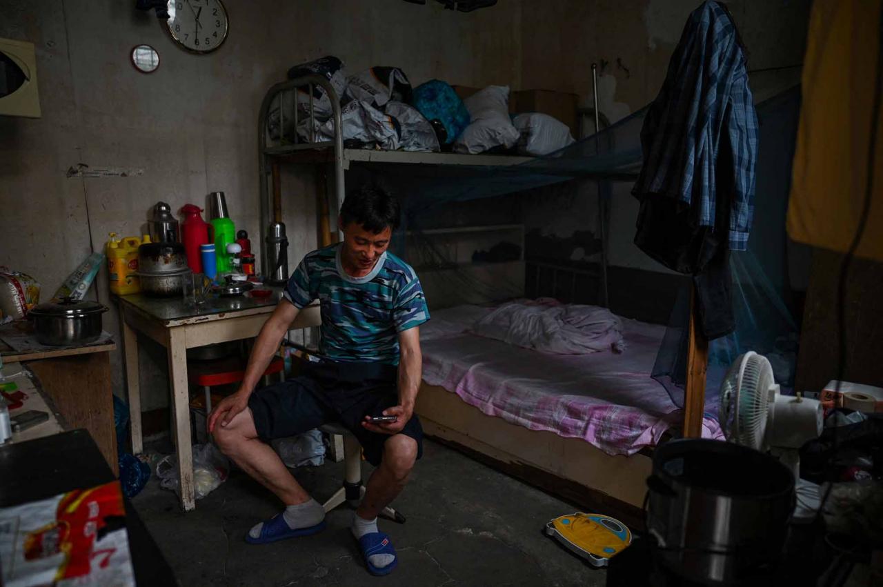 This photo taken on June 21, 2022 shows a deliveryman in his room in the Laoximen neighbourhood of Shanghai's Huangpu district. - Bricked-up doorways, crumbling facades, and a small group of defiant locals: one of Shanghai's oldest neighbourhoods is barely clinging to life as the city presses ahead with demolition and redevelopment plans. (Photo by Hector RETAMAL / AFP)