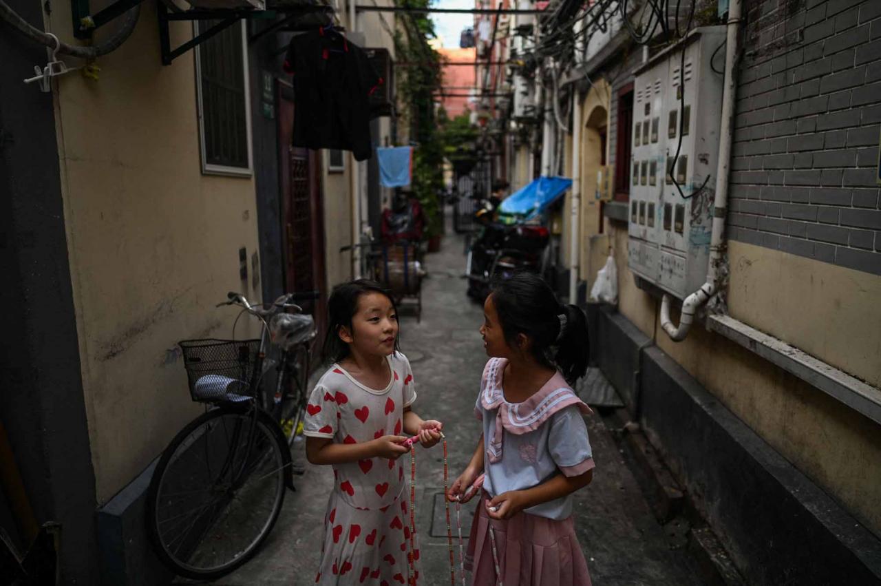 This photo taken on July 3, 2022 shows children playing in an alleyway in the Laoximen neighbourhood of Shanghai's Huangpu district. - Bricked-up doorways, crumbling facades, and a small group of defiant locals: one of Shanghai's oldest neighbourhoods is barely clinging to life as the city presses ahead with demolition and redevelopment plans. (Photo by Hector RETAMAL / AFP)