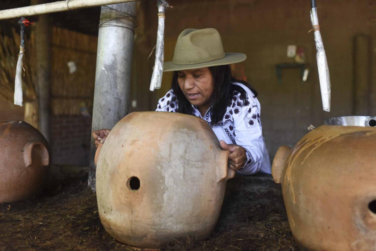 Sosima Olivera, who is member of a collective that runs the mezcal factory Tres Colibries (Three Hummingbirds), moves a clay pot used for distillation at the factory in Villa Sola de Vega, Oaxaca State, Mexico, on July 26, 2022. - Craft distillers fear mezcal will become victim of its own success. The fast-growing popularity of Tequila's lesser-known cousin is raising concerns about its sustainability as strong demand means that more land, water and firewood are needed to grow the agave plants and distill the smoky spirit. Faced with the boom, craft producers are committed to saving wild species by planting them and showcasing the artisanal process behind the liquor. (Photo by Pedro PARDO / AFP)