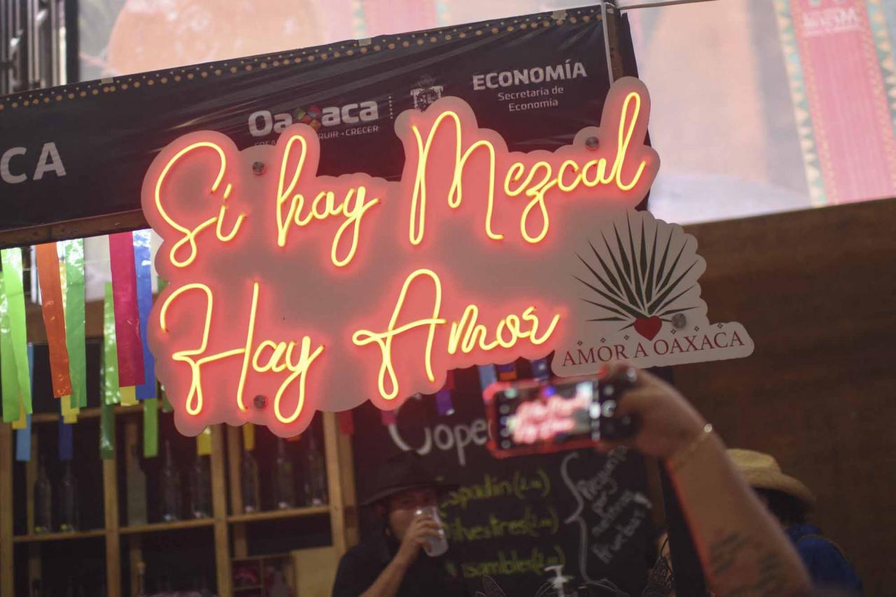 A neon signs reads "If There is Mezcal, There is Love" at a stand selling mezcal at the Mezcal Fair in Oaxaca, Mexico, on July 26, 2022. - Craft distillers fear mezcal will become victim of its own success. The fast-growing popularity of Tequila's lesser-known cousin is raising concerns about its sustainability as strong demand means that more land, water and firewood are needed to grow the agave plants and distill the smoky spirit. Faced with the boom, craft producers are committed to saving wild species by planting them and showcasing the artisanal process behind the liquor. (Photo by Pedro PARDO / AFP)