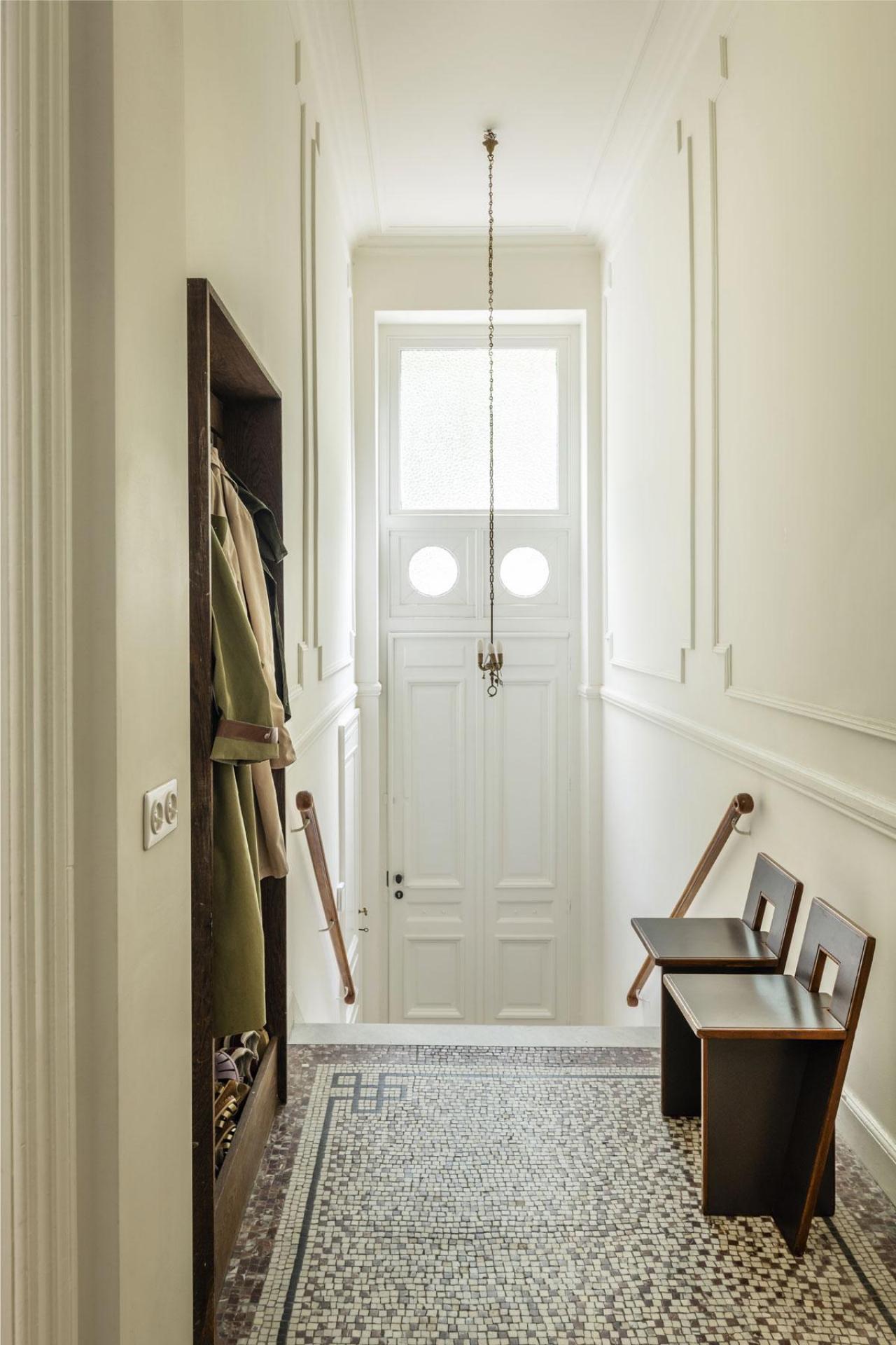 L’entrée d’une demeure qui ne renie pas ses origines néoclassiques mais expose deux chaises dénichées chez Bea Mombaers.