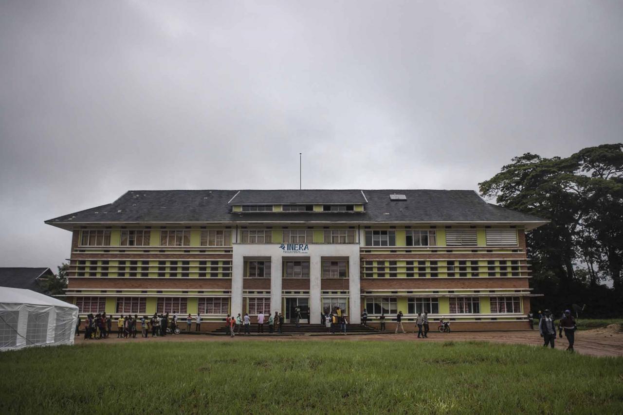 People stand in front of the administrative building of the National Institute for Agronomic Study and Research (INERA) in Yangambi, 100 km from the city of Kisangani, in the province of Tshopo, in the northeast of the Democratic Republic of the Congo on September 2, 2022. - The site, renowned during the time of Belgian colonisation for its research in tropical agronomy, hosts a herbarium that has more than 6000 species. (Photo by Guerchom Ndebo / AFP)