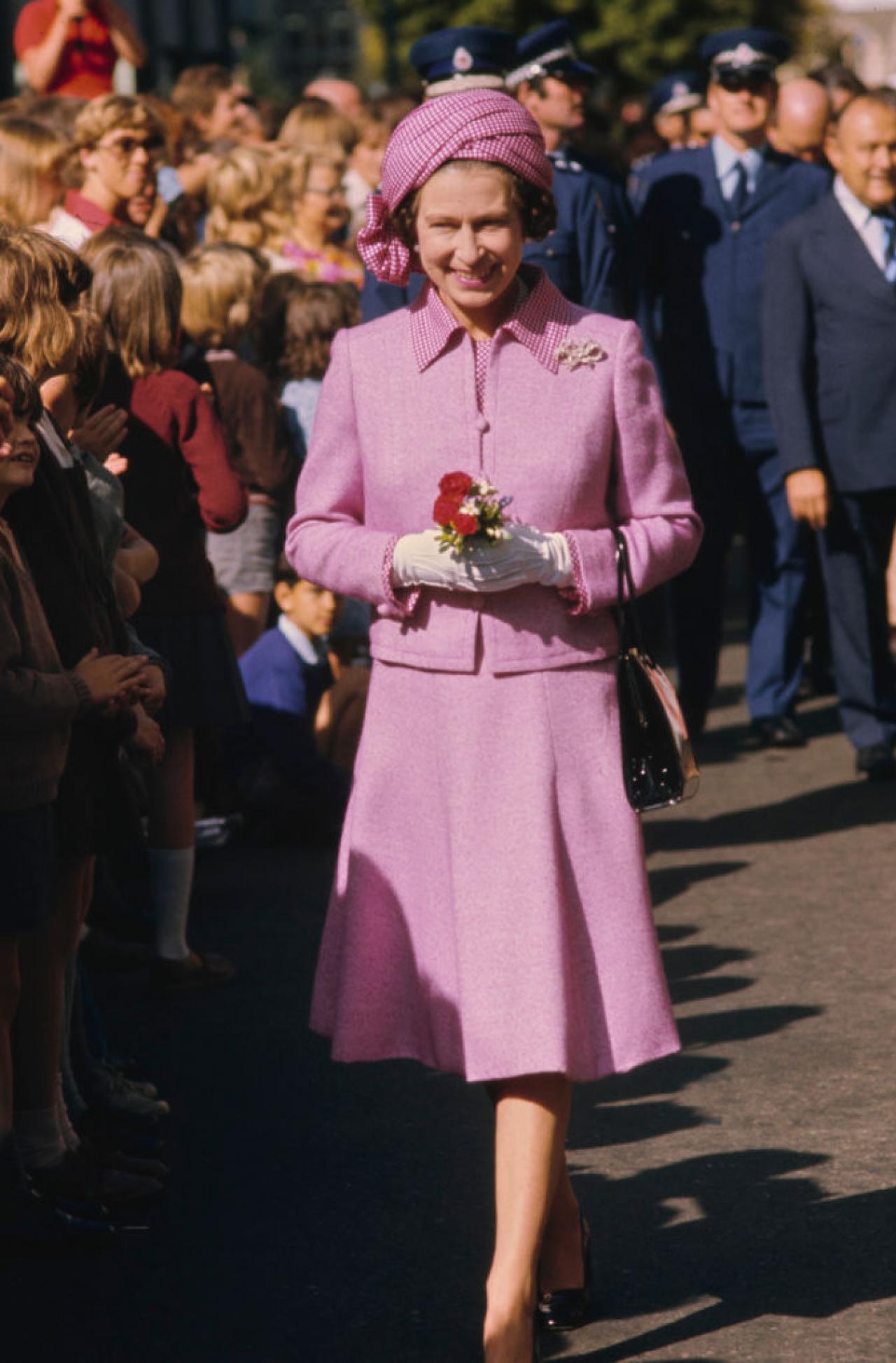 British Royal Queen Elizabeth ll, wearing a lilac suit with a checked collar and matching turban-style hat, during a walkabout in Wellington, New Zealand, 27th February 1977. The visit is part of the Queen's Silver Jubilee tour. (Photo by Serge Lemoine/Hulton Archive/Getty Images)