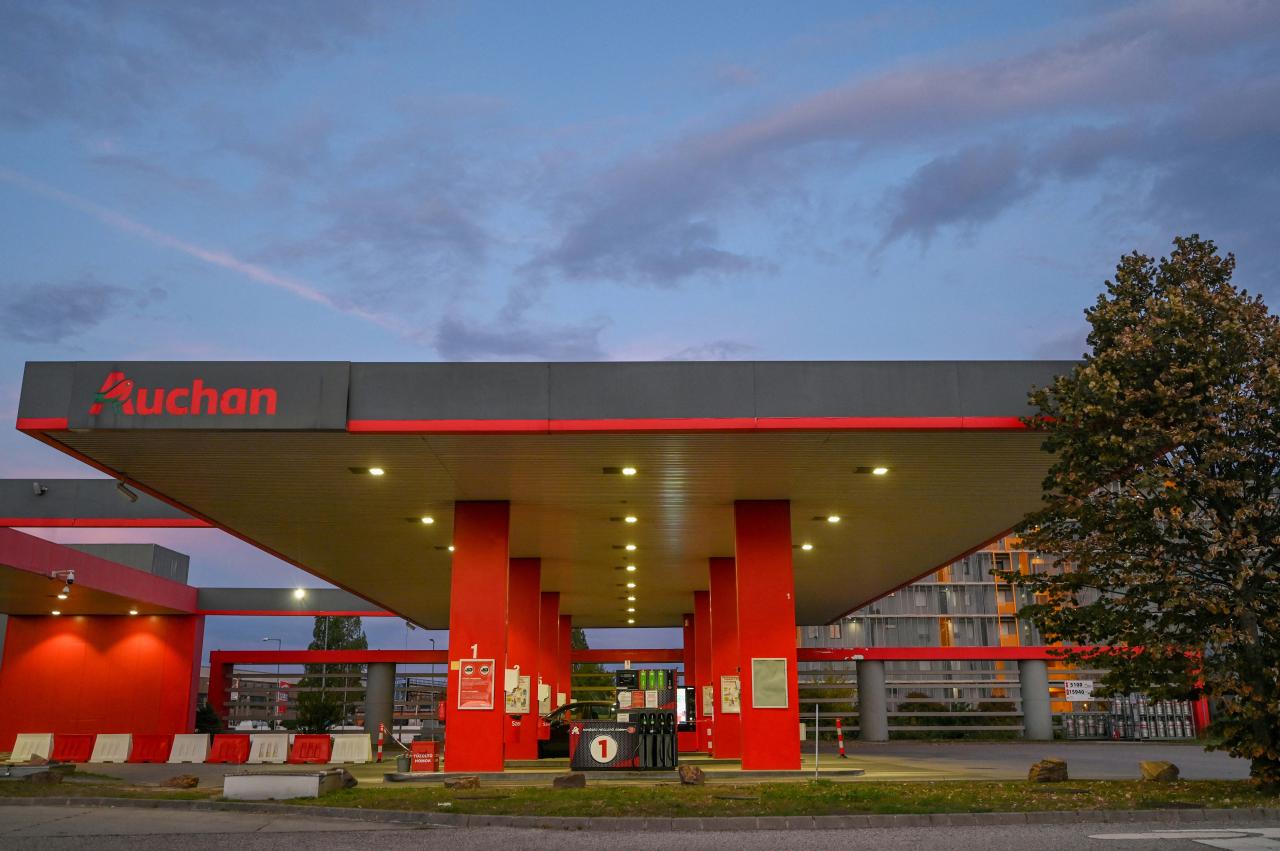 This photograph taken on August 29, 2022 in Budapest's 11th district, Hungary, shows a petrol station French multinational company Auchan, at dusk. - A vintage pump in the Vietnamese hills; a Madrid petrol station topped with a giant sombrero; a multi-coloured futuristic fuel outlet in Dubai  whatever its form the humble filling stop, emblem of our modern societies, would appear to be running out of road. (Photo by Attila KISBENEDEK / AFP)