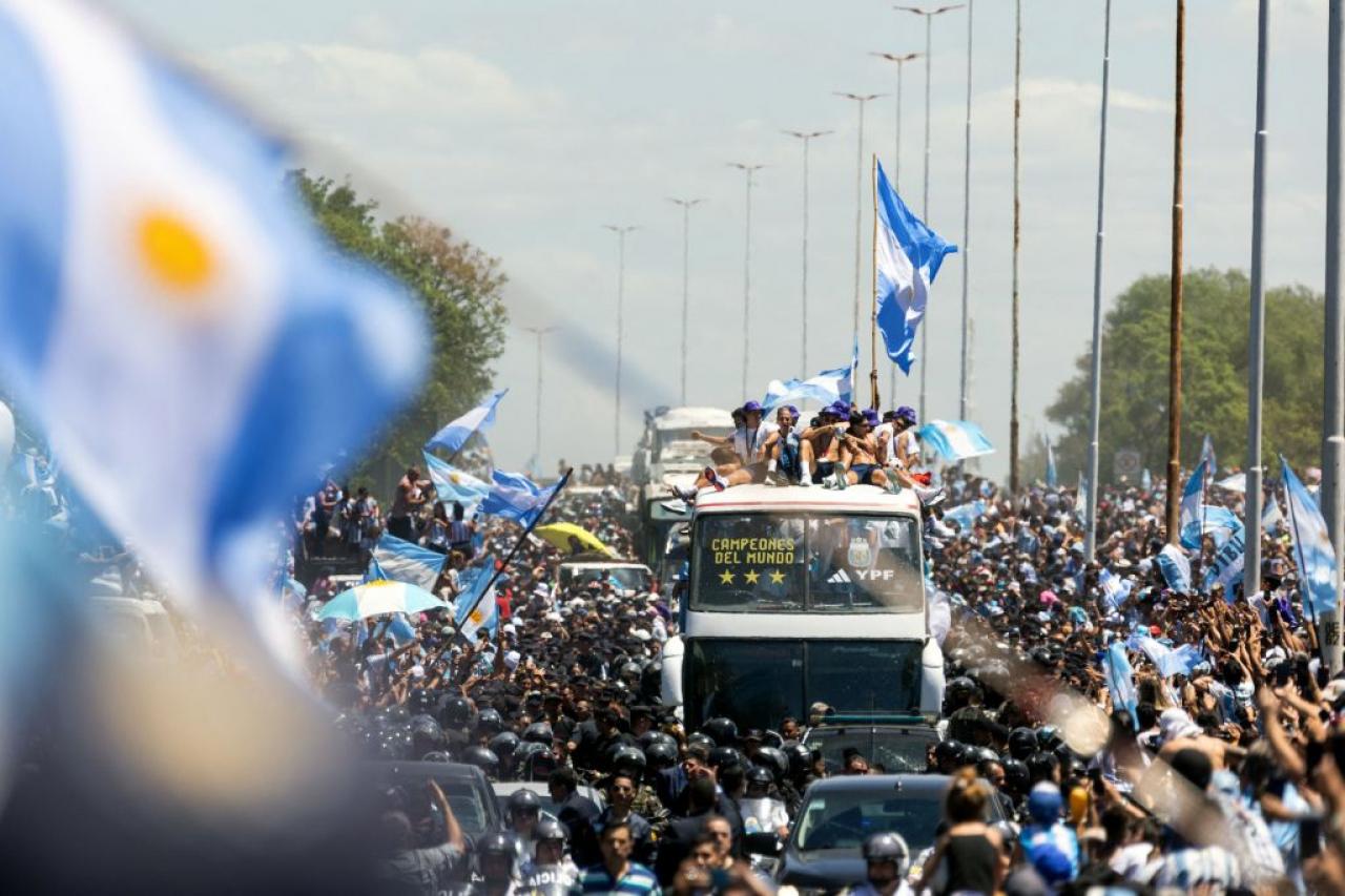 TOPSHOT - Fans of Argentina cheer as the team parades on board a bus after winning the Qatar 2022 World Cup tournament, in Buenos Aires province, on December 20, 2022. - Millions of ecstatic fans are expected to cheer on their heroes as Argentina's World Cup winners led by captain Lionel Messi began their open-top bus parade of the capital Buenos Aires on Tuesday following their sensational victory over France. (Photo by TOMAS CUESTA / AFP) (Photo by TOMAS CUESTA/AFP via Getty Images)