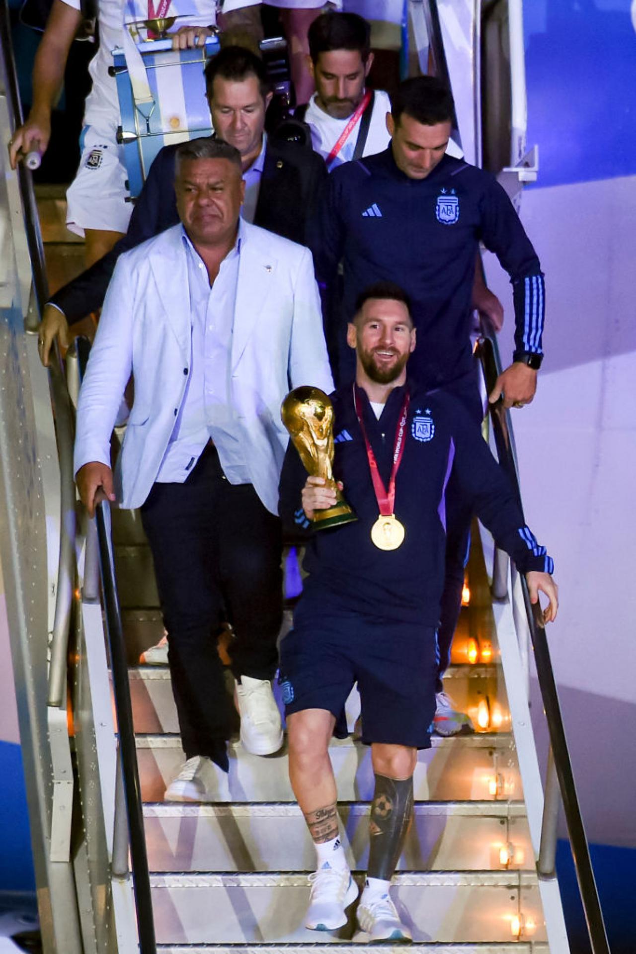 BUENOS AIRES, ARGENTINA - DECEMBER 20: Lionel Messi, Claudio Tapia, Lionel Scaloni get off the plane with the FIFA World Cup during the arrival of the Argentina men's national football team after winning the FIFA World Cup Qatar 2022 on December 20, 2022 in Buenos Aires, Argentina. (Photo by Marcelo Endelli/Getty Images)