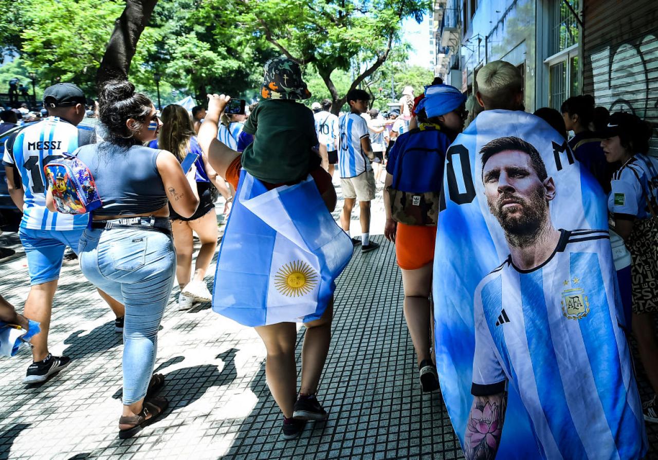 BUENOS AIRES, ARGENTINA - DECEMBER 20: Fans of Argentina wear flags with the image of Lionel Messi as they gather for the victory parade of the Argentina men's national football team after winning the FIFA World Cup Qatar 2022 on December 20, 2022 in Buenos Aires, Argentina. (Photo by Marcelo Endelli/Getty Images)