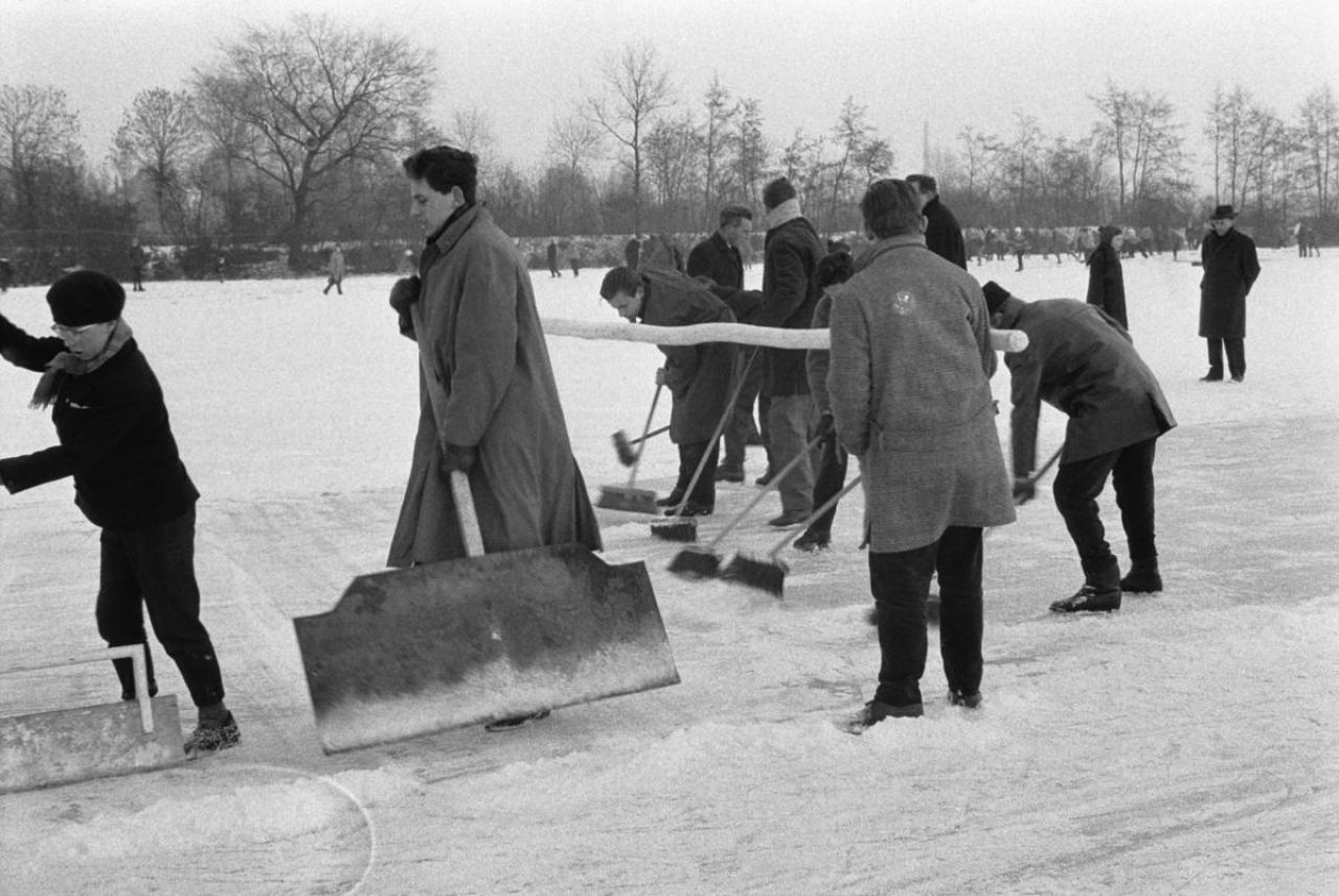 Schaatsen op het domein Vijvershof te Sint-Michiels in 1963. Vóór het schaatsplezier kan beginnen, moet eerst de sneeuw geruimd van de bevroren vijver.
