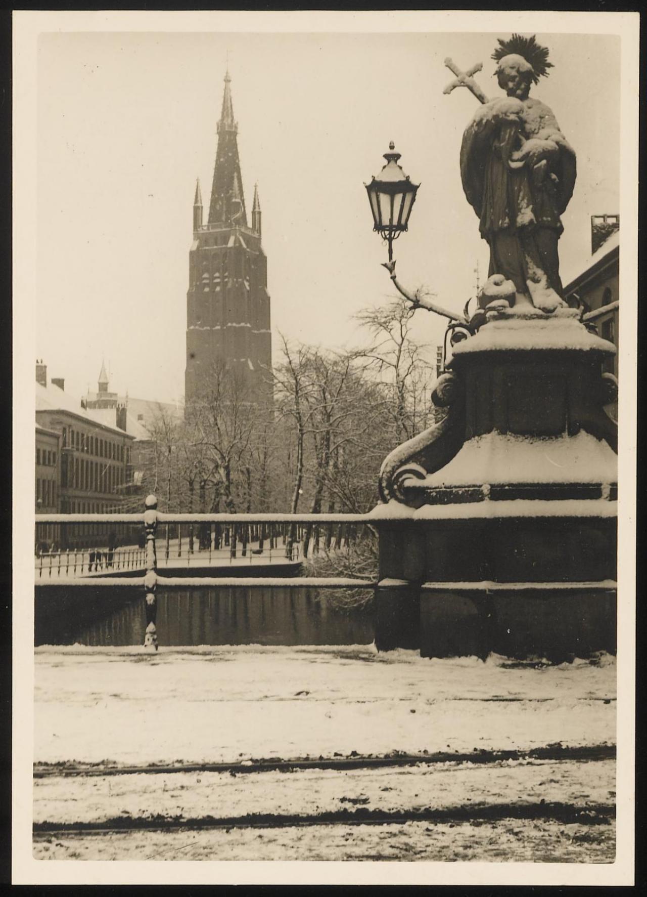 De Nepomucenusbrug in de sneeuw rond 1910. Op het bruggenhoofd staat het standbeeld van Sint-Jan Nepomucenus. Links op de achtergrond zien we de Onze-Lieve-Vrouwekerk.