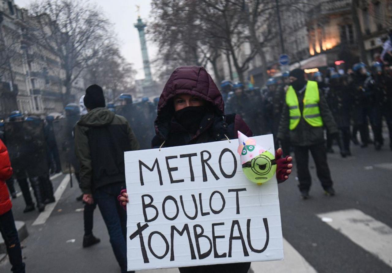 A demonstrator holds a sign reading 'Metro, job, tomb'  during a rally called by French trade unions in Paris on January 19, 2023. - A day of strikes and protests kicked off in France on January 19, 2023 set to disrupt transport and schooling across the country in a trial for the government as workers oppose a deeply unpopular pensions overhaul. (Photo by Christophe ARCHAMBAULT / AFP) (Photo by CHRISTOPHE ARCHAMBAULT/AFP via Getty Images)