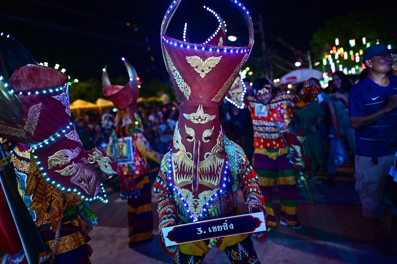 This photo taken on June 23, 2023 shows festival-goers wearing ghost masks and colorful costumes while dancing at night during the annual Phi Ta Khon carnival or ghost festival in Dan Sai district in northeastern Thailands Loei Province. (Photo by MANAN VATSYAYANA / AFP)