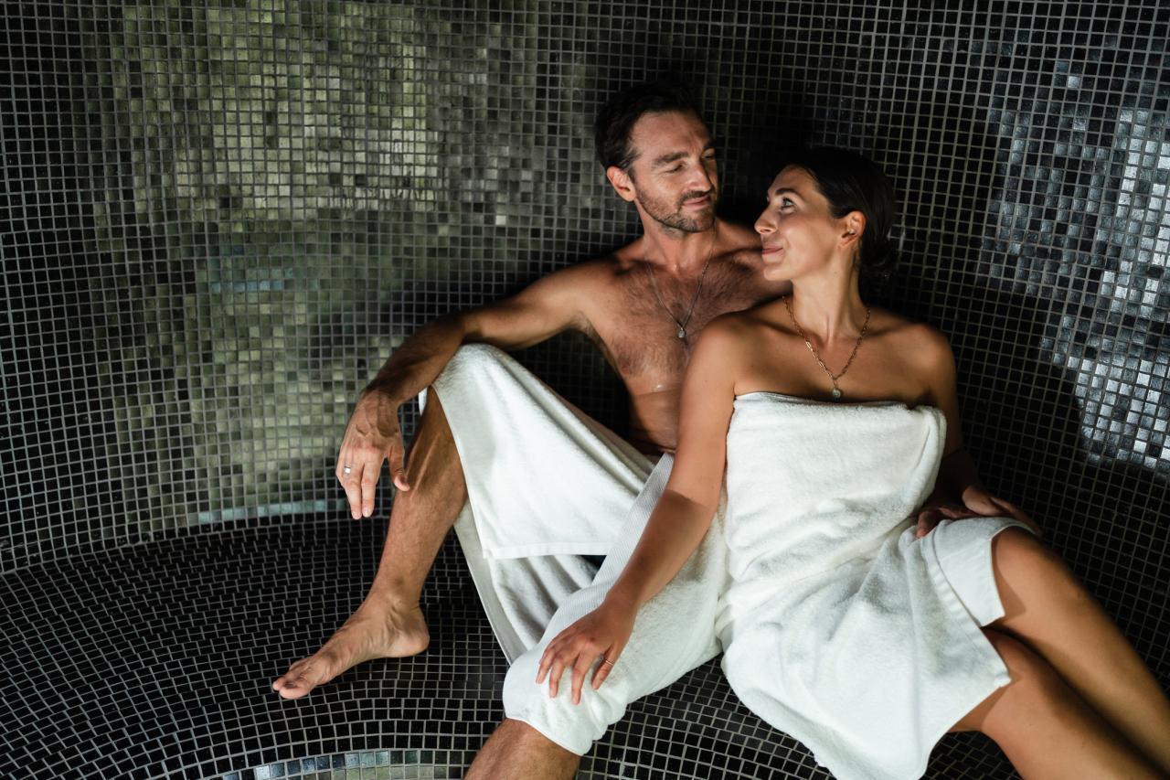 Smiling couple is sitting in a private sauna on their vacation in a luxury villa.