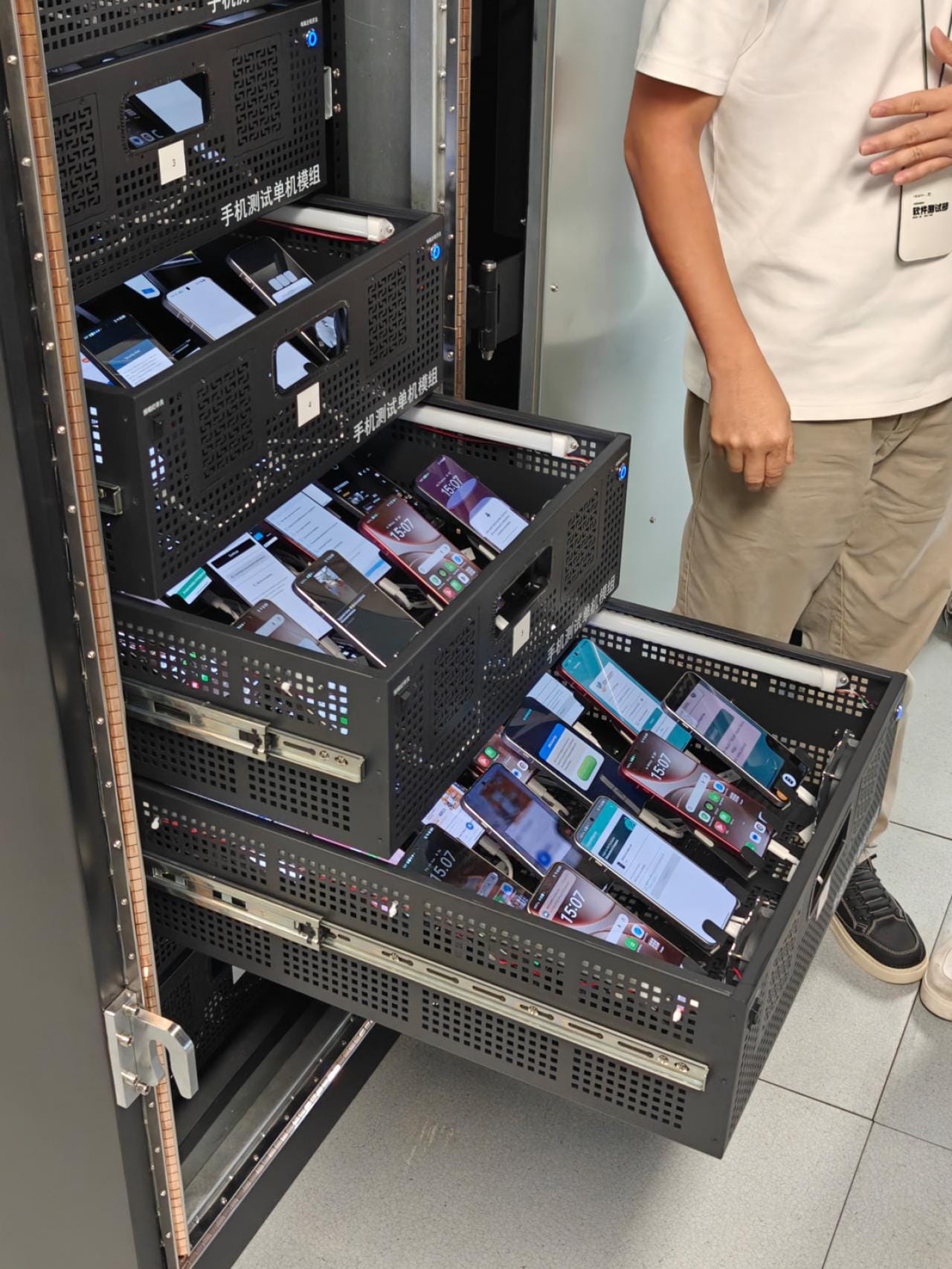 Verspreid over 200 cabinets worden hier om en nabij de 20.000 smartphones simultaan getest.