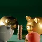 Opgestapelde munten omringd door spaarvarkens.