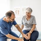 Dokter onderzoekt de knie van een oudere dame.