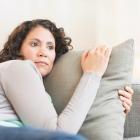 Vrouw op middelbare leeftijd ligt met gemende gevoelens in de zetel.