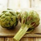 Twee verse artisjokken op een snijplank.
