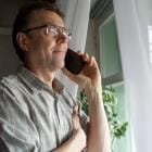 Man met bril van middelbare leeftijd met telefoon aan het oor.