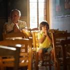 Oudere man en jong kind bidden samen in de kerk