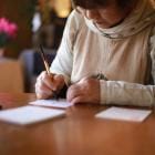 Vrouw schrijft tekst op een kaart op tafel in de woonkamer