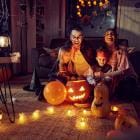 Ouders en kinderen zitten buiten op het terras omrings met Halloweenversiering