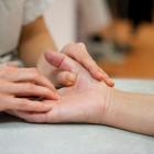 Zorgverlener behandelt de duim van een patiënt via manipulatie van het gewricht.