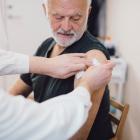 Mannelijke arts geeft vaccin aan oudere man in medische kliniek