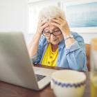 Oudere dame met de handen in het haar voor laptop.