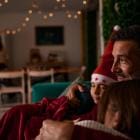 Een gelukkige vader omhelst zijn twee kinderen op de bank en kijkt naar een kerstfilm