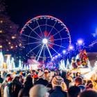 Zicht over mensenmassa aan kerstmarkt brussel met het rad op de achtergrond.