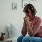 Depressieve blanke vrouw van rond de 60 alleen in haar slaapkamer.