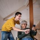 Kleinzoon en grootmoeder gebruiken samen de smartphone.