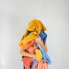 Persoon houdt hoop gebruikte kledij vast.