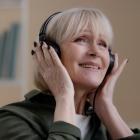 een zorgeloze senior dame met oordopjes die naar muziek luistert en geniet van de liedjes.