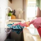 Vrouw gebruikt poetsmiddelen om het aanrecht van de keuken proper te maken.